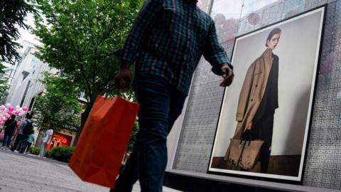 A shopper carries a red bag past a storefront in Washington, DC, US, on Thursday, May 30, 2024. 