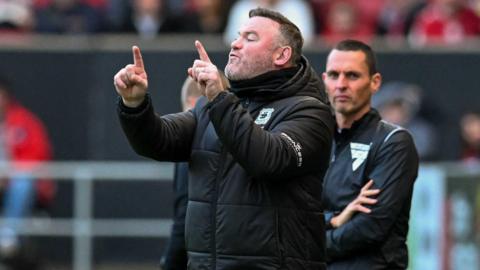 Wayne Rooney holds both hands in the air, delivering instructions to his players