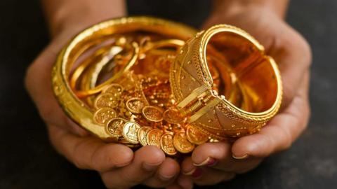 A cupped pair of hands filled with gold jewelry