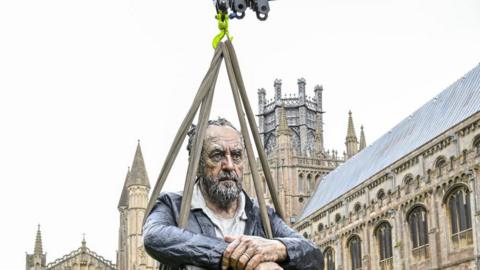 Sculpture of man being hoisted