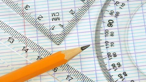 GCSE maths image: A close up view of a ruler, protractor, triangular ruler and pencil on lined paper