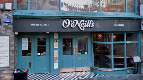 Front of closed doors of O'Neill's on Wardour Street painted blue with black and white tiles at the entrance floor, and a curved front window. 