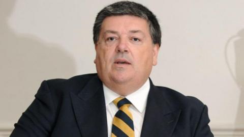 A man wearing a black blazer with a black and yellow tie.