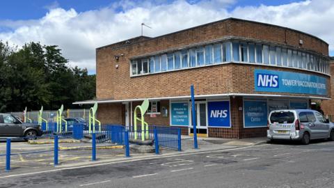 The picture shows the former bus stops and one of the buildings on the site.  It is covered in NHS livery as the site was once a Covid vaccination centre.