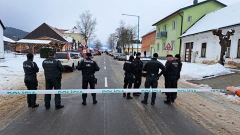 Eight police stand on a cordoned-off road in the middle of a town