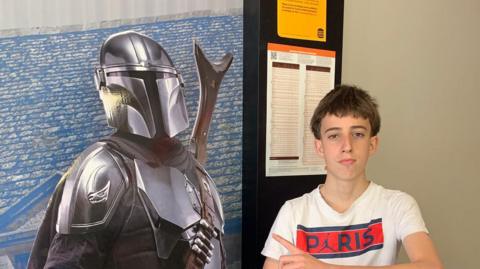 A boy posing with a cutout of a Star Wars character