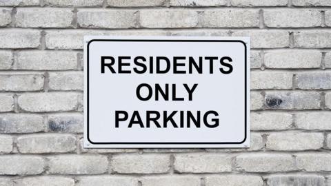 A white sign which says residents only parking