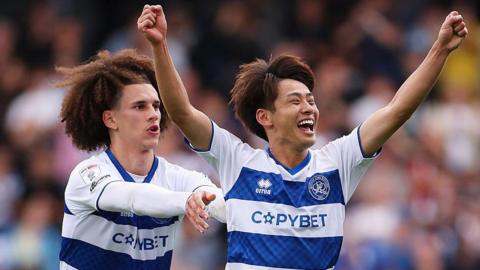 Koki Saito celebrates with arms aloft after scoring for QPR, with Rayan Kolli behind him