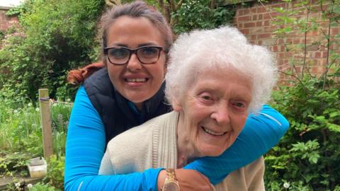 A younger woman hugs an older woman