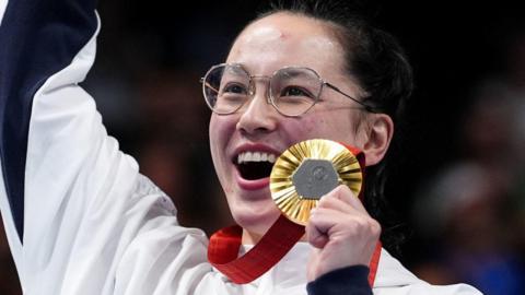 A smiling Alice Tai posing with her Paralympic gold medal at the Paris 2024 games