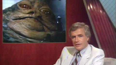 Iain Johnstone in front of an image of Jabba the Hutt from Star Wars.