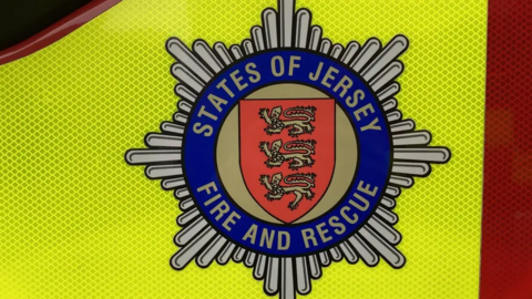 The side of a fire service vehicle, with the States of Jersey Fire and Rescue emblem on the side.