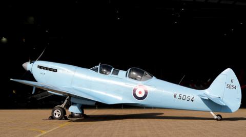 A side view of a spitfire painted in a baby blue colour.
