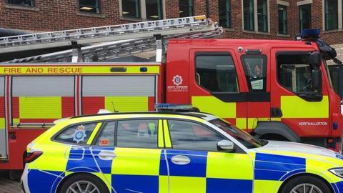 Police car parks alongside a fire engine.