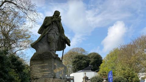 Victor Hugo statue in Candie Gardens, Guernsey, with buildings and trees in the background