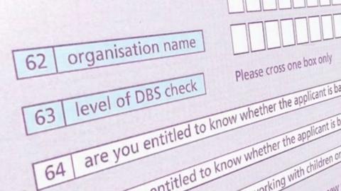 A still image of an online DBS form. The words 'level of DBS check' are visible. The form is coloured shades of blue and purple. 