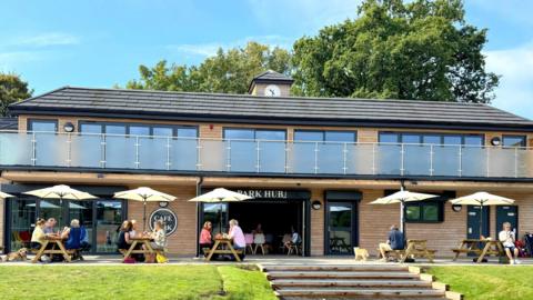 People dining alfresco at a café based in a community hub.
