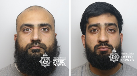 A composite image of two men's mugshots. One on the left is bald with a black beard. The one of the right has a black bears and short black hair. They both look at the camera expressionless. There is a Dyfed-Powys Police watermark on it.