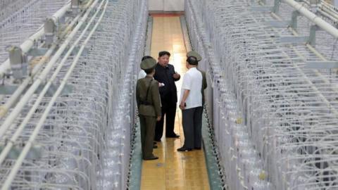 Kim walks past rows of centrifuges and talks to military officials at the Nuclear Weapons Institute