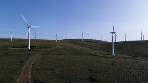 A windfarm on a sunny day, witharound a dozen wind turbines visible