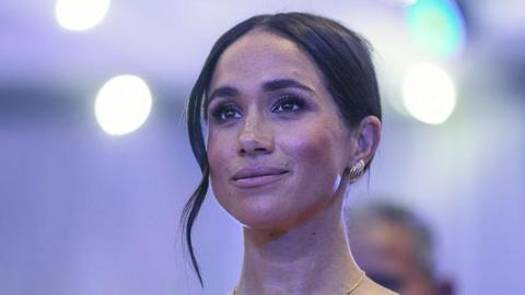 A close up of a woman with dark hair in an up-do and silver earrings