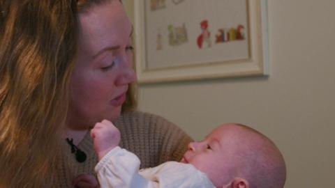 A mother sings to her baby in a close-up shot.