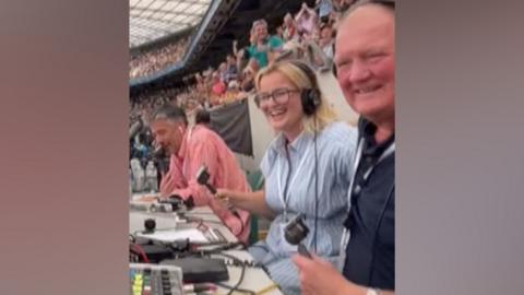 A commentary team celebrates at the end of a rugby match
