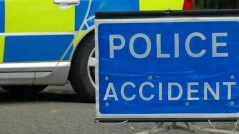 A blue and white sign stating Police Accident, with a police car in the background.