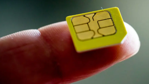 A close-up of a small yellow card on the end of an oustretched finger