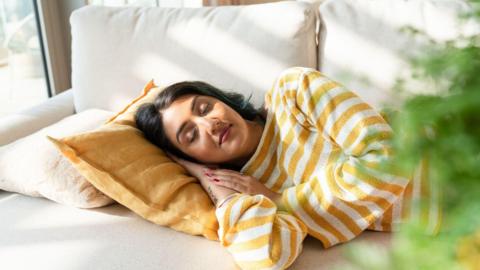A person lying on a sofa asleep.
