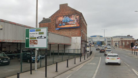 Google image showing the existing illuminated advertisement on Witham. There is a road sign in the foreground directing motorists to the Humber Bridge, with North Bridge visible in the distance. 
