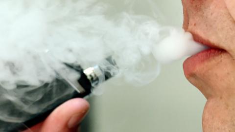 close up of a male exhaling smoke after taking a puff from a vape