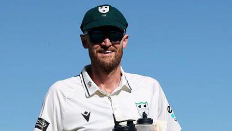 Olly Hannon-Dalby leaving the field at New Road Worcester carrying water bottles having played his last game on loan for the county