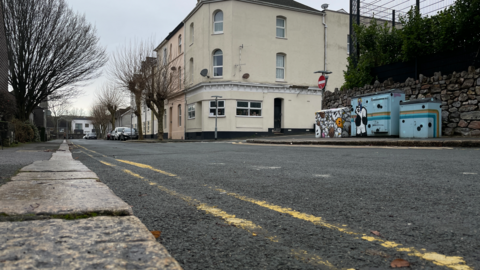A picture of the scene where the incident took place. It is a large road with double yellow lines on it.