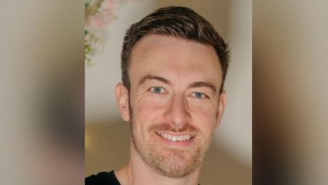 Danny Burney in a close-up photo. He has short, brown hair and a beard. He is smiling at the camera.