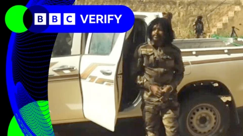 A screengrab showing the arrest of the RSF commander known as Abu Lulu. In the footage he is wearing military fatigues and is being led out of a jeep. In the background armed men can be seen watching on. 