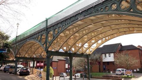 A view of the side and underneath of the bridge showing iron beams across three spans. 