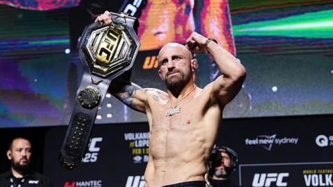 Alexander Volkanovski raises his featherweight title at the UFC 325 news conference
