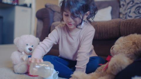 A child playing with teddy bears in a living room.