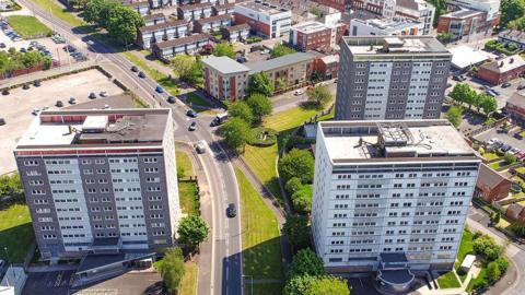 Aerial view of the three Avenham tower blocks, two grey and white clad ones to the right of a road and one to the left