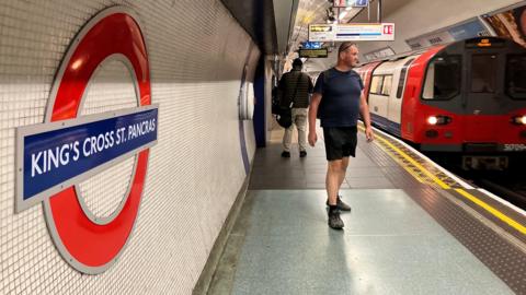 King's Cross platform shows passengers, Tube roundel and a train destined for Morden