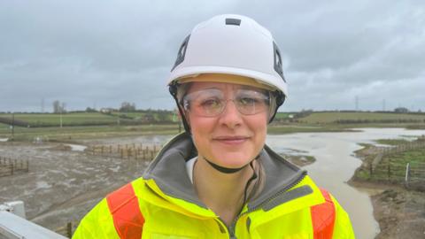 A woman in hard hat and high vis clothing 