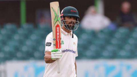 Shan Masood raises his bat after reaching 100 for Leicestershire against Gloucestershire