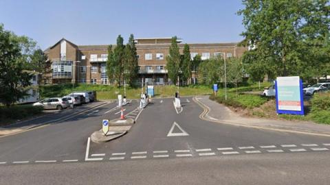 Entrance to hospital with a brown-bricked building in the background.