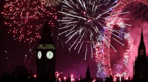 Red and gold fireworks illuminate the night sky behind the shadowy silhouette of the Elizabeth Tower, home of Big Ben, in Westminster. 