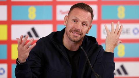 Craig Bellamy wears a dark jacket and top