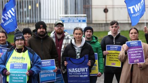 A group of men and women from the NASUWT union hold up placards and flags during previous strike action