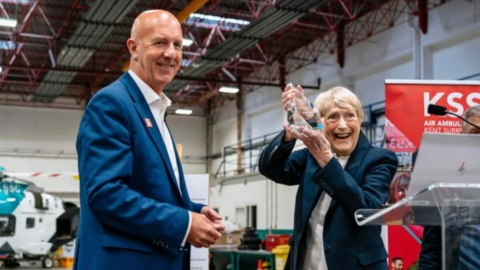 KSS founder Kate Chivers lifts a glass trophy - her lifetime achievement award - and smiles at the camera alongside chief executive David Welch