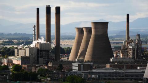 An oil refinery with chimney stacks, and hills in the background