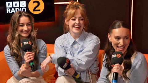 Remember Monday's members smiling and speaking with microphones in the BBC Radio 2 studio